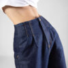 Jean Mom fit, tiro alto, tono azul indigo crudo, pliegues cosidos, cierre con cremallera