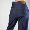 Jean Mom fit, tiro alto, tono azul indigo crudo, pliegues cosidos, cierre con cremallera